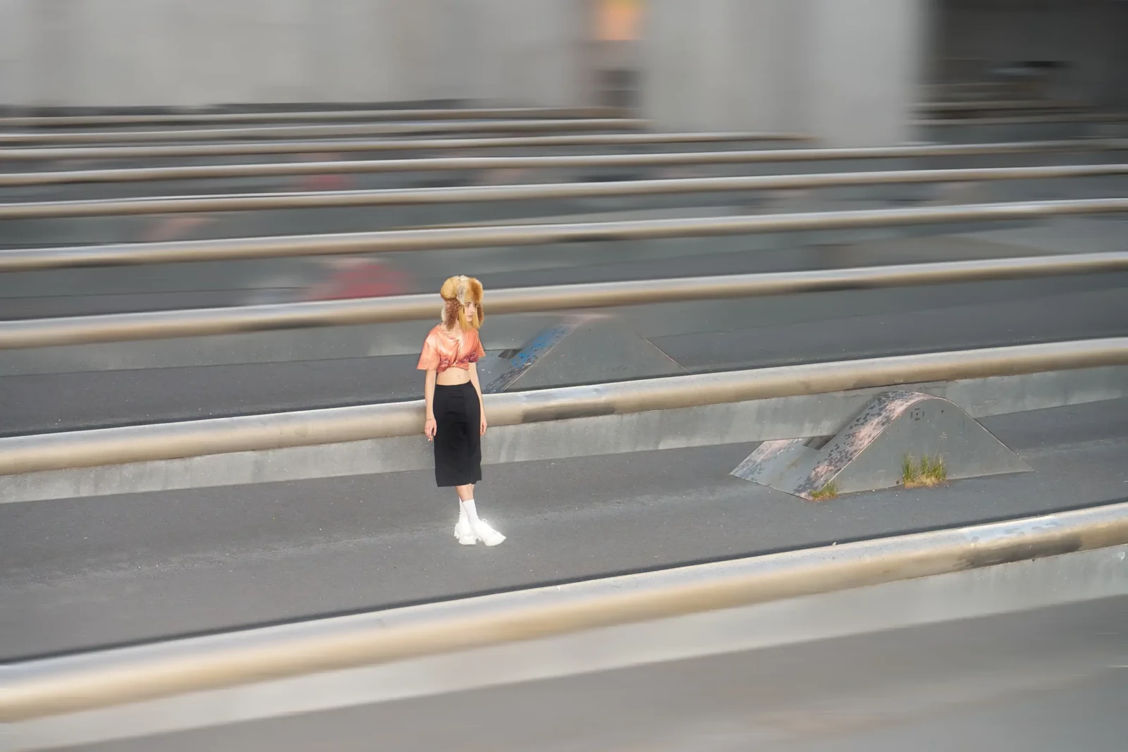 Blonde model in a pink top, dark skirt and white boots photographed with motion blur on urban steps.