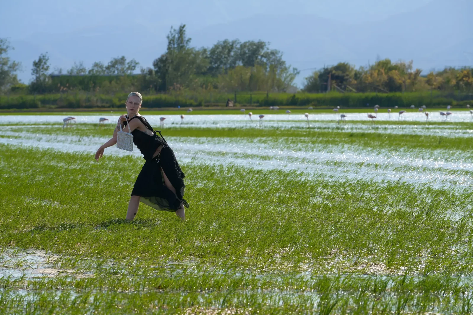 Model in black clothing running across a flooded grassy field.