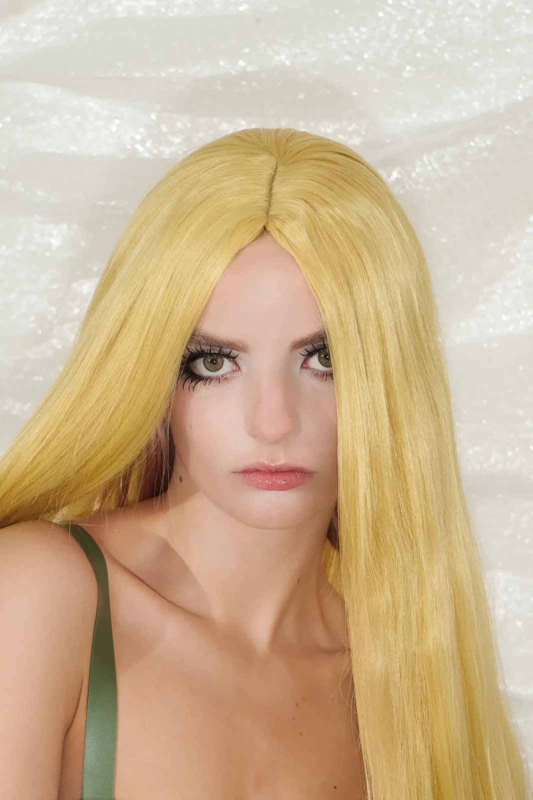Close-up beauty portrait of a blonde model with long straight hair and a pale top.