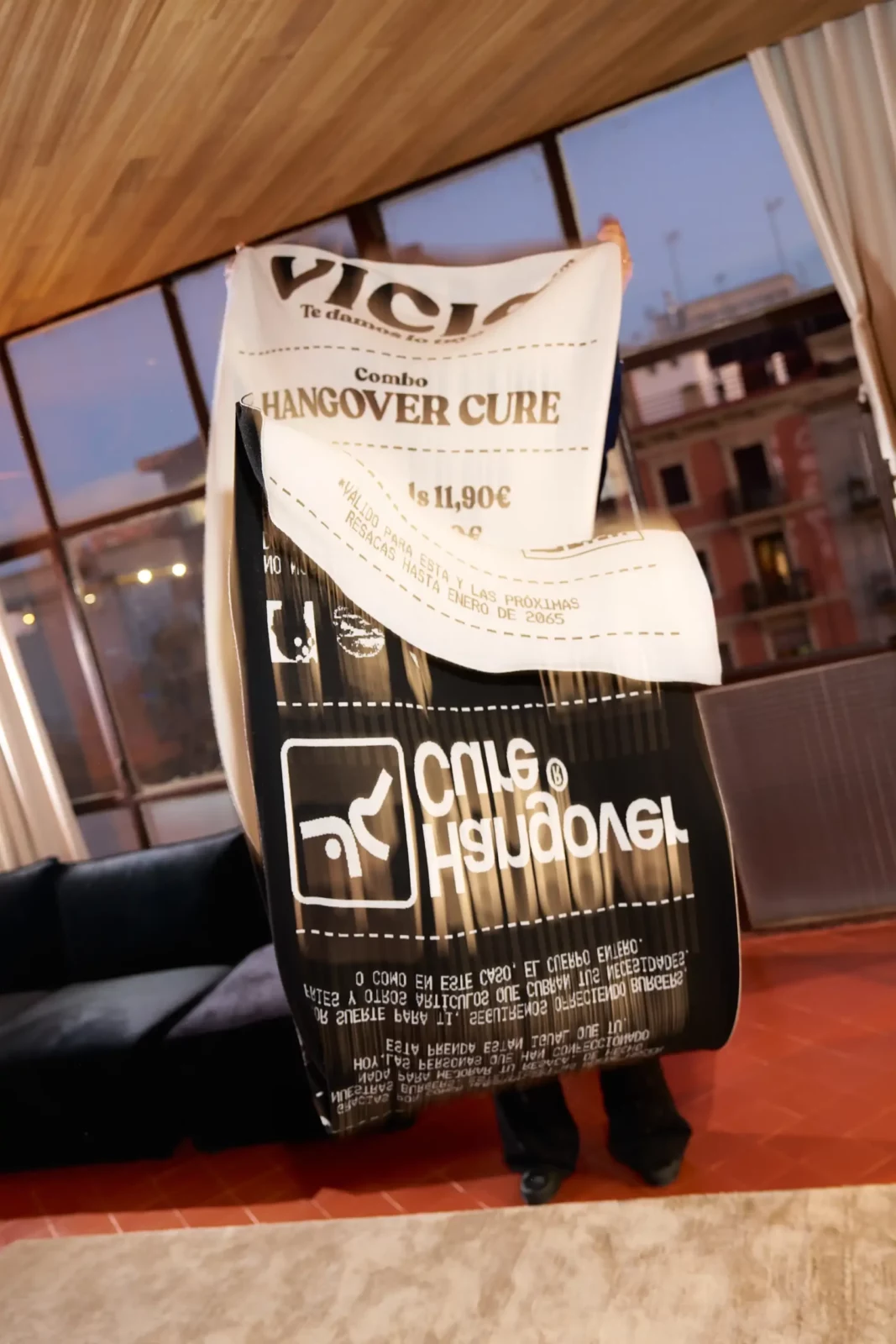 Close-up of printed newspapers with oversized headings held up in front of a city window.
