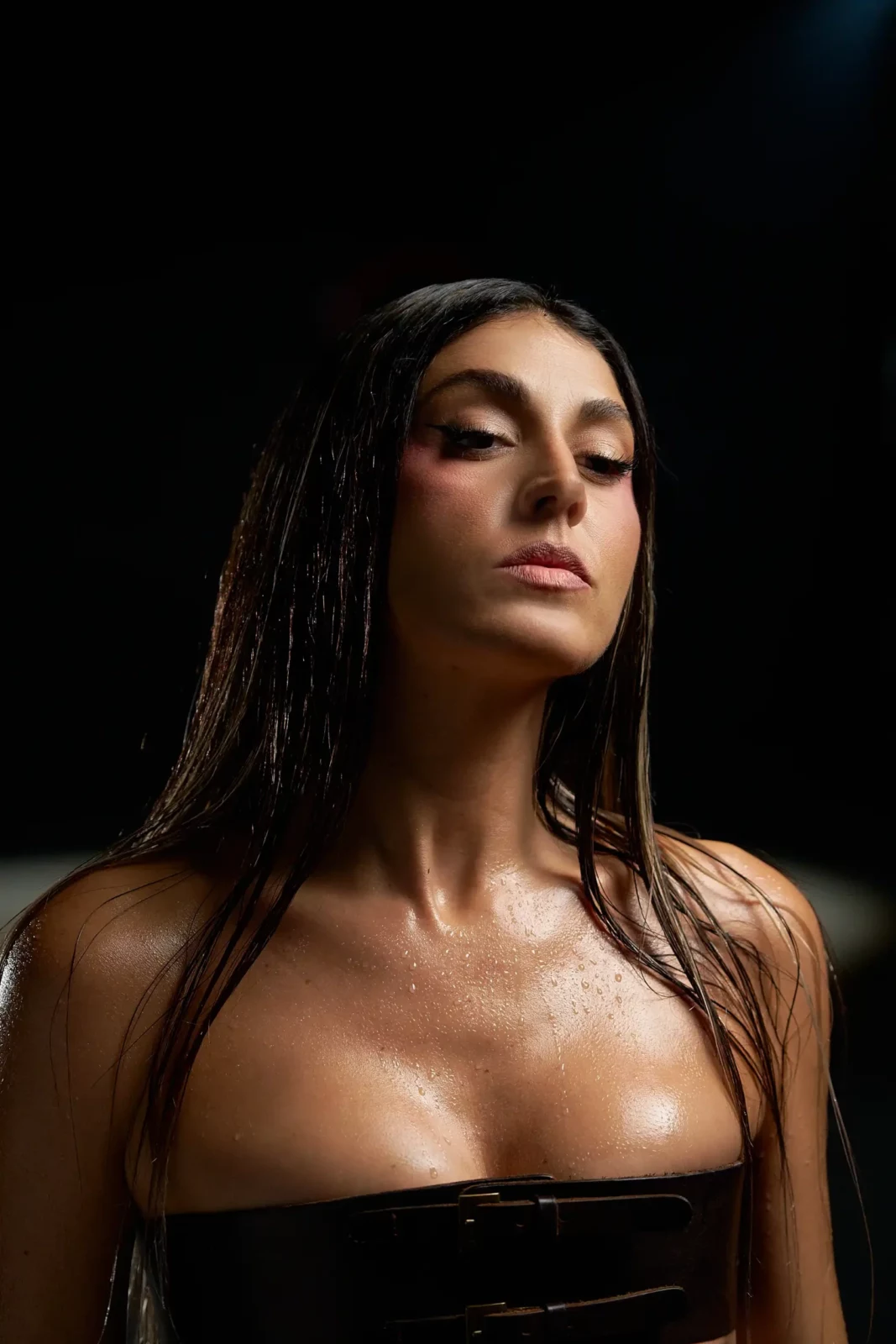 Dramatic close-up portrait of Queralt Lahoz in a black strapless top against a dark backdrop.