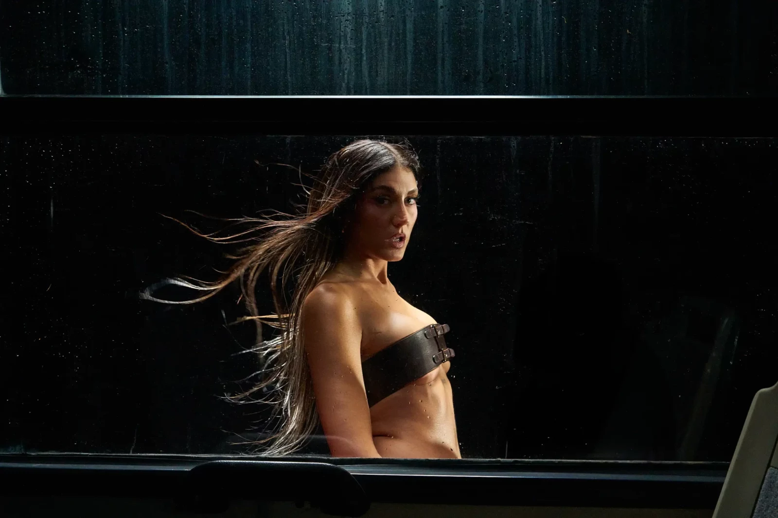 Side portrait of Queralt Lahoz wearing a black bandeau top with long hair blown by the wind.