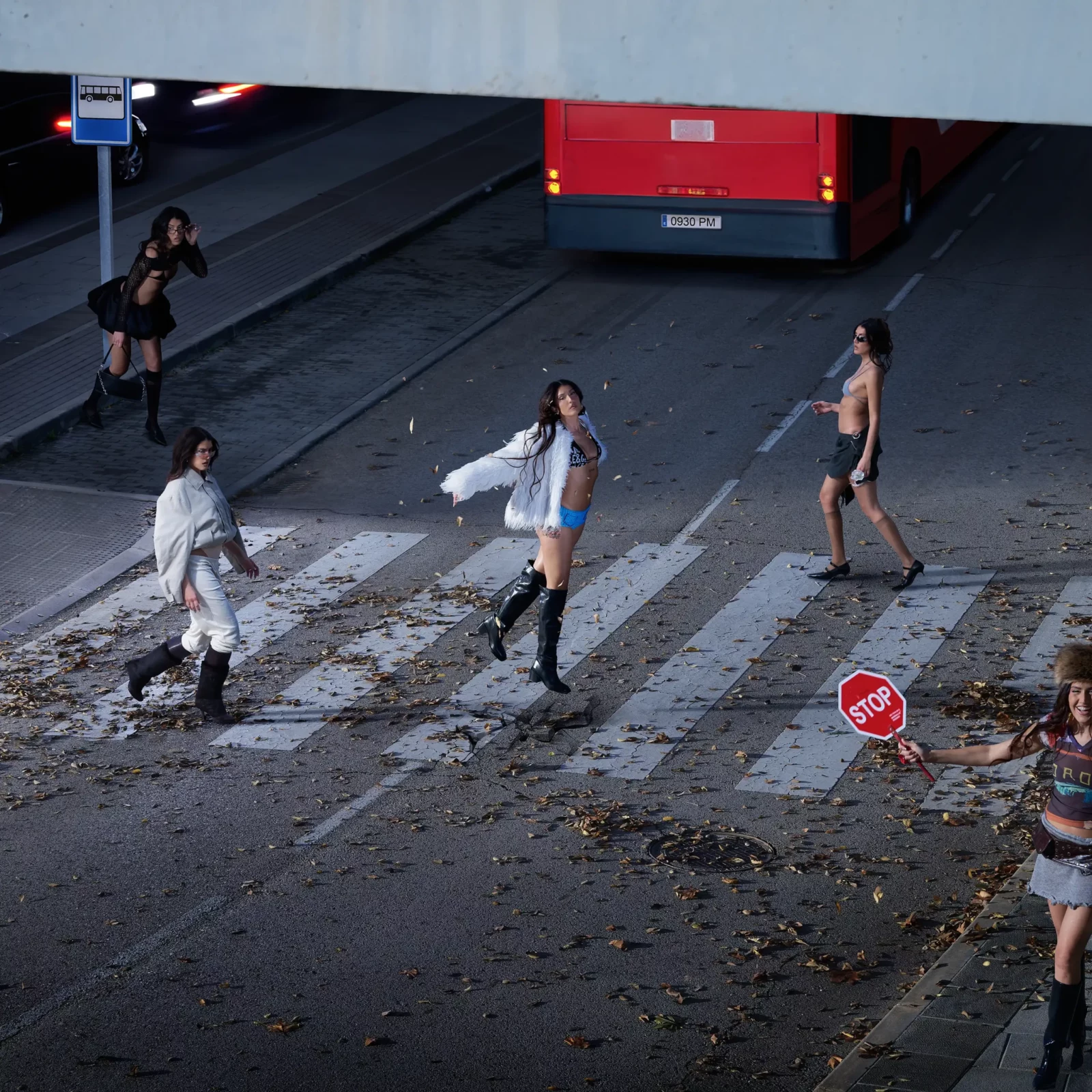 Elevated city-street photograph of Queralt Lahoz and other performers crossing a road near a red bus.
