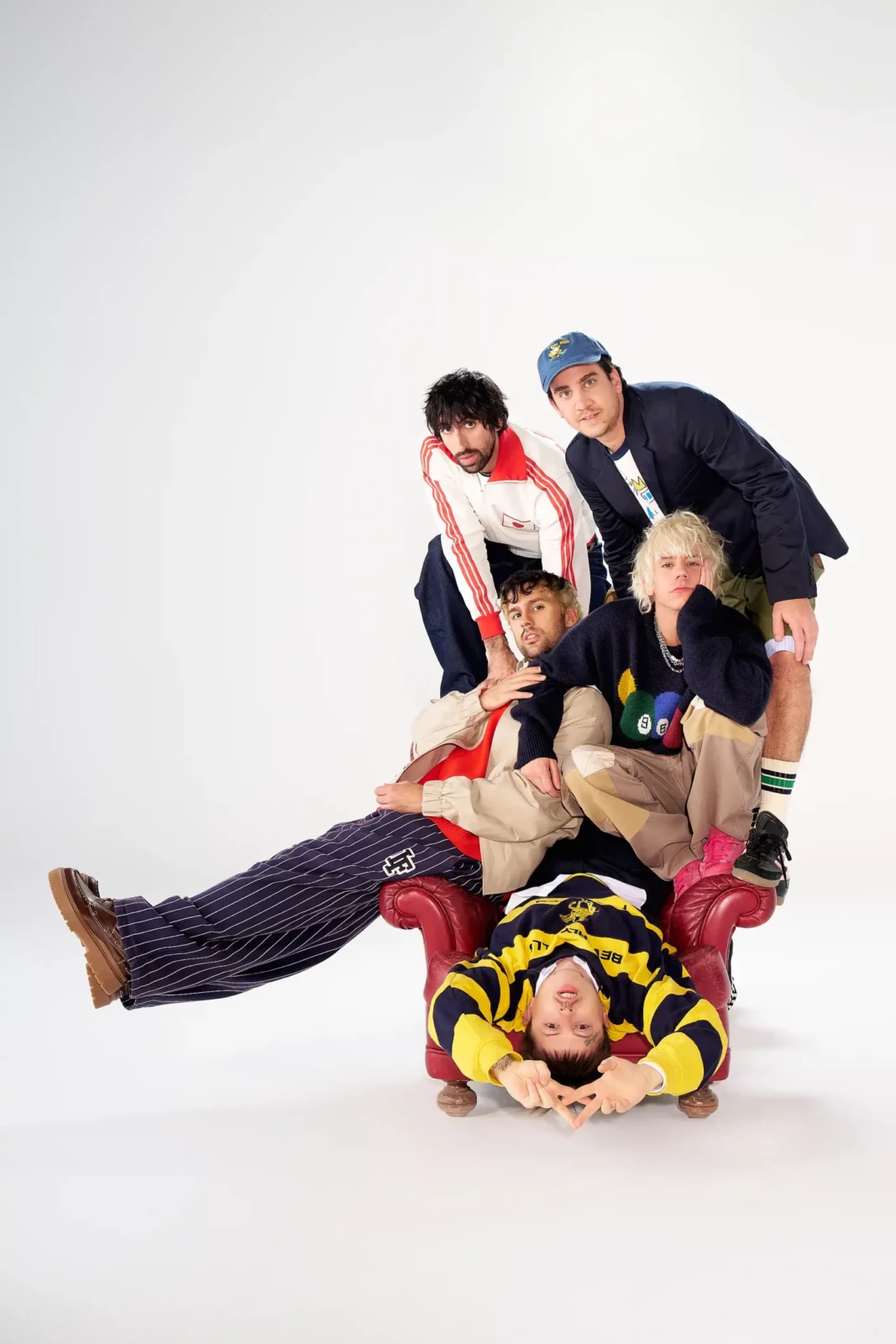 Cupido band members piled together in a playful studio portrait against a white background.