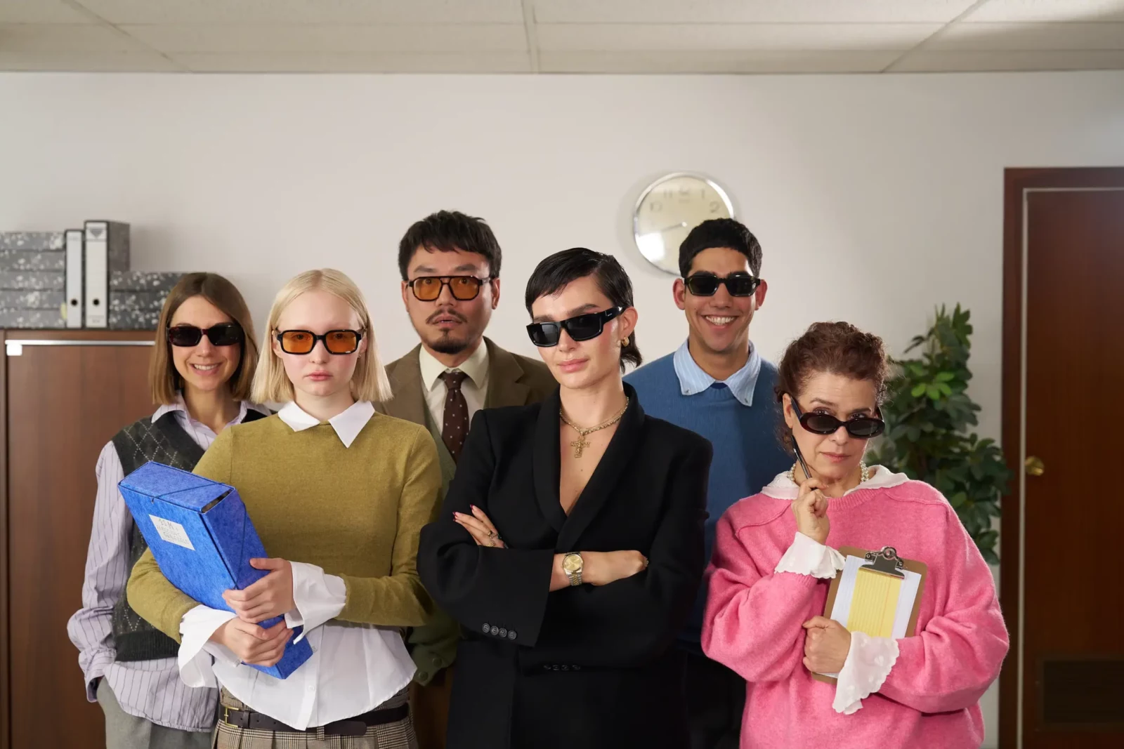 Group of five office workers in sunglasses holding colored folders in a retro corporate setting.