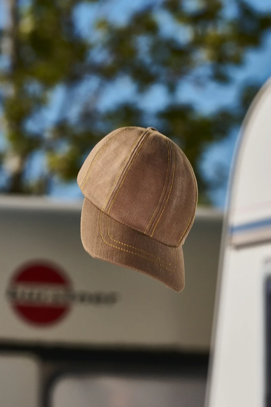 Close-up of a beige baseball cap floating against a soft outdoor background.