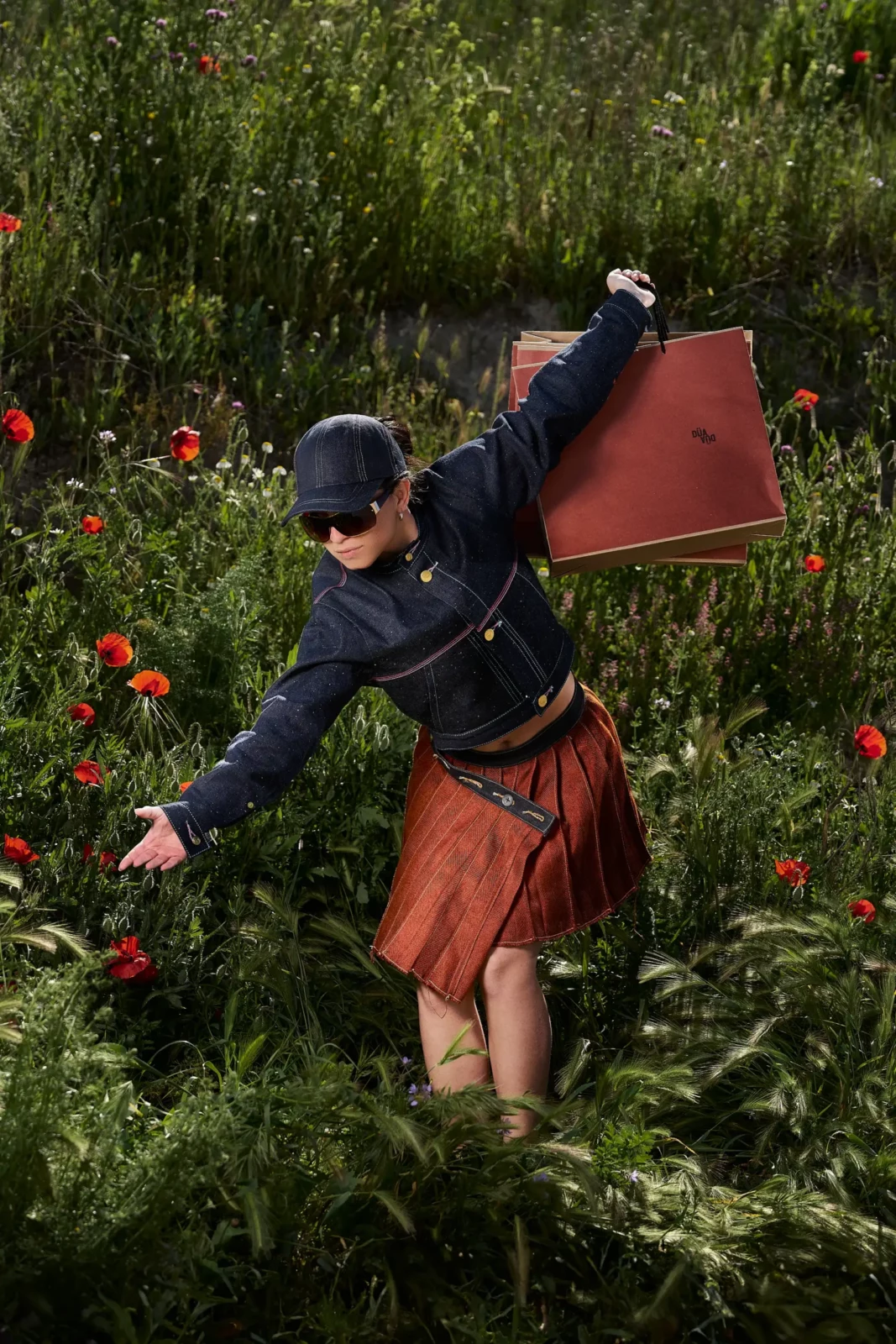 Young woman in a navy top, red skirt and cap balancing beside a tree-lined path.