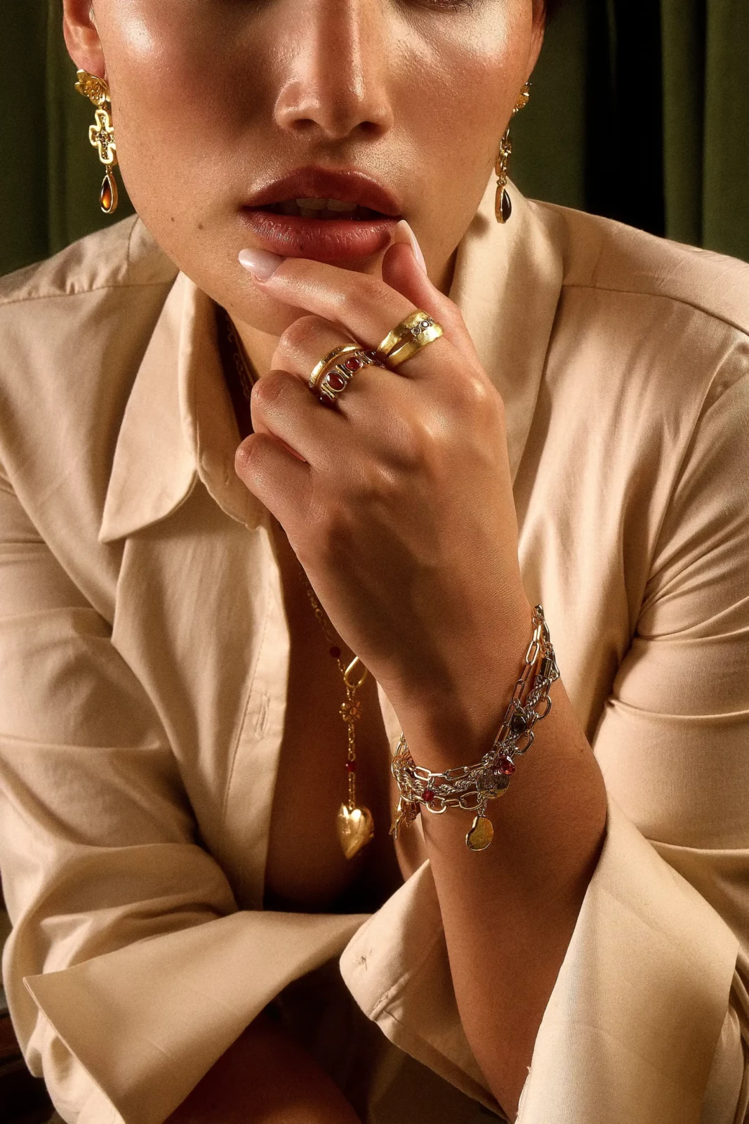 Close-up fashion portrait highlighting layered silver rings, bracelet and necklace.