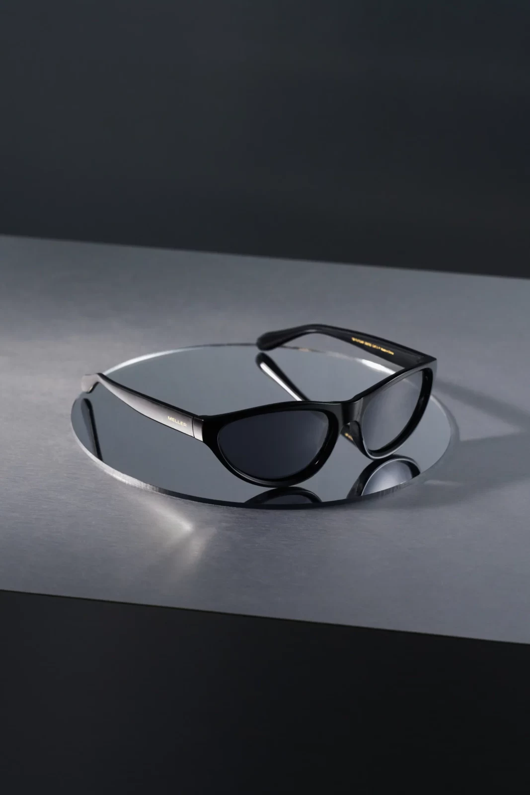 Close-up product photograph of black-rimmed sunglasses with dark lenses on a gray surface.