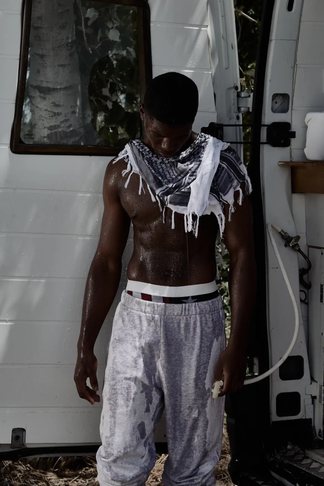 Model wearing a distressed sleeveless outfit standing in the doorway of a truck.