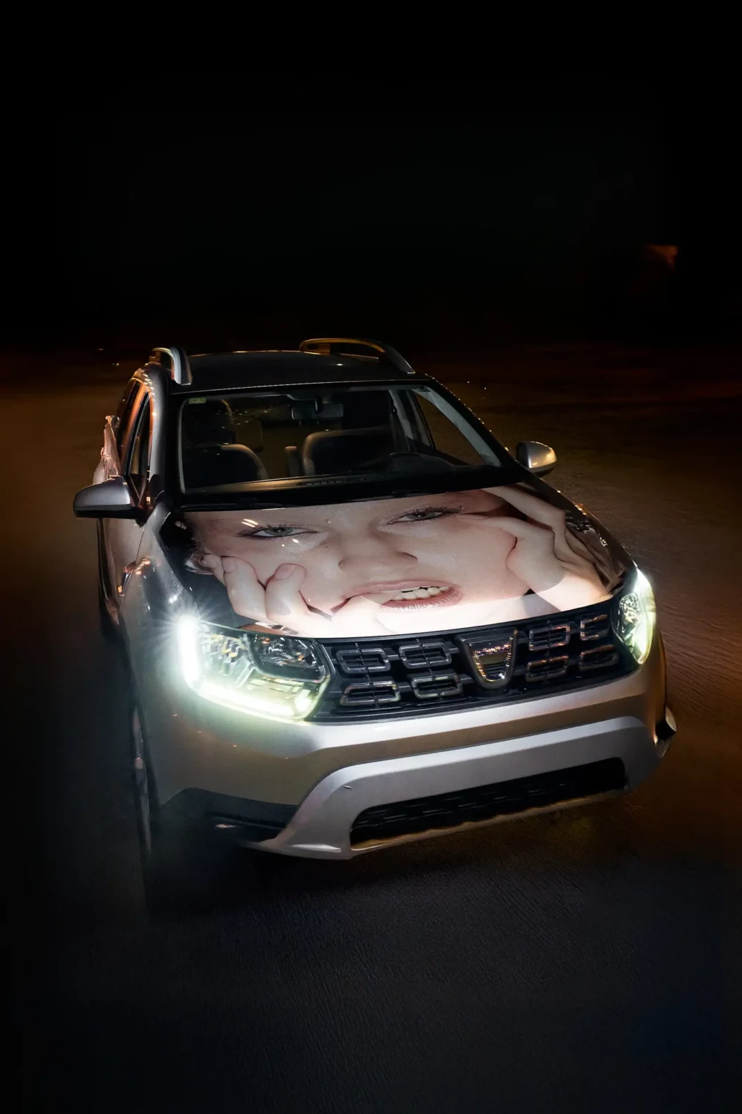Front view of a car parked at night with illuminated headlights and graphic artwork across its hood.