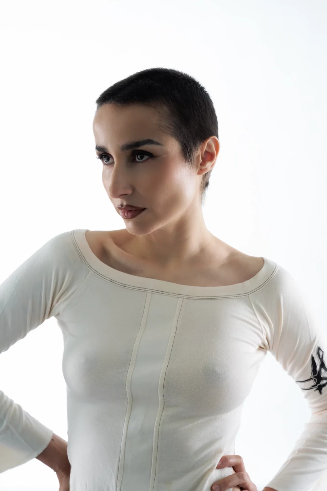 Close portrait of Zahara wearing a sheer white top with her hair pulled back against a bright white background.
