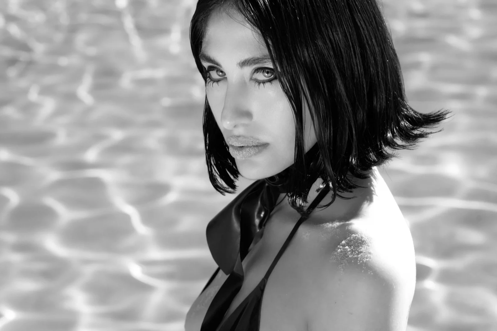Black-and-white close-up portrait of a dark-haired woman wearing a black halter bikini top.