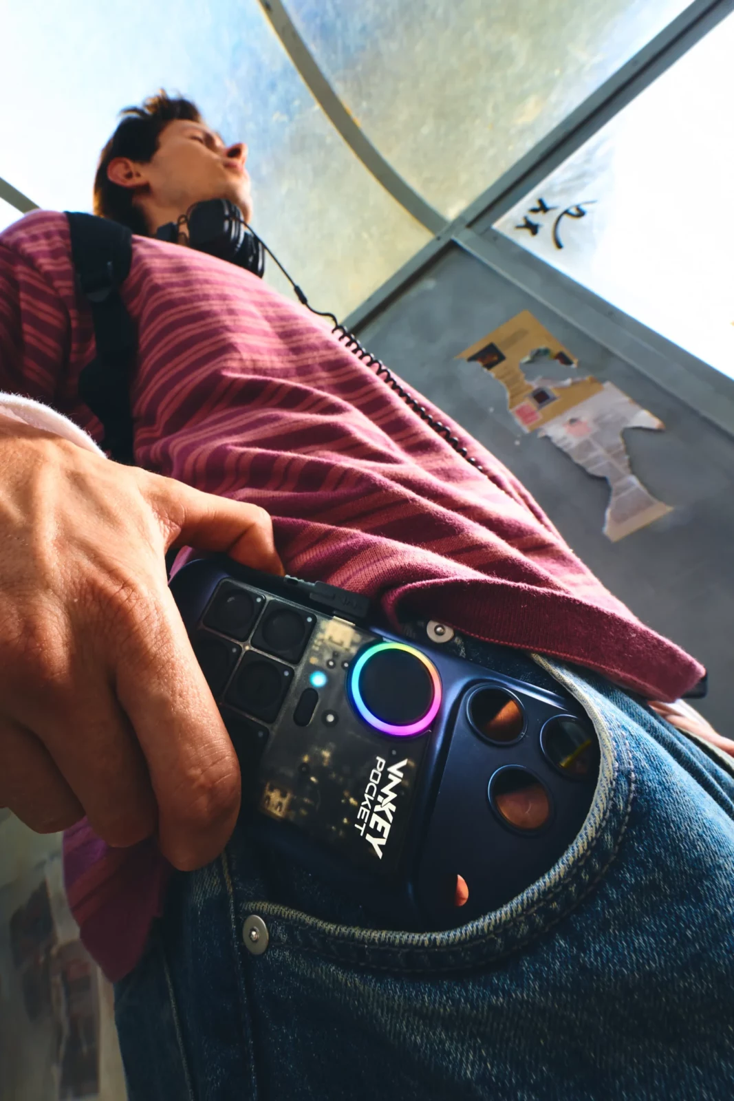 Low-angle fashion photograph of a striped shirt and jeans with a handheld audio device clipped near the waist.