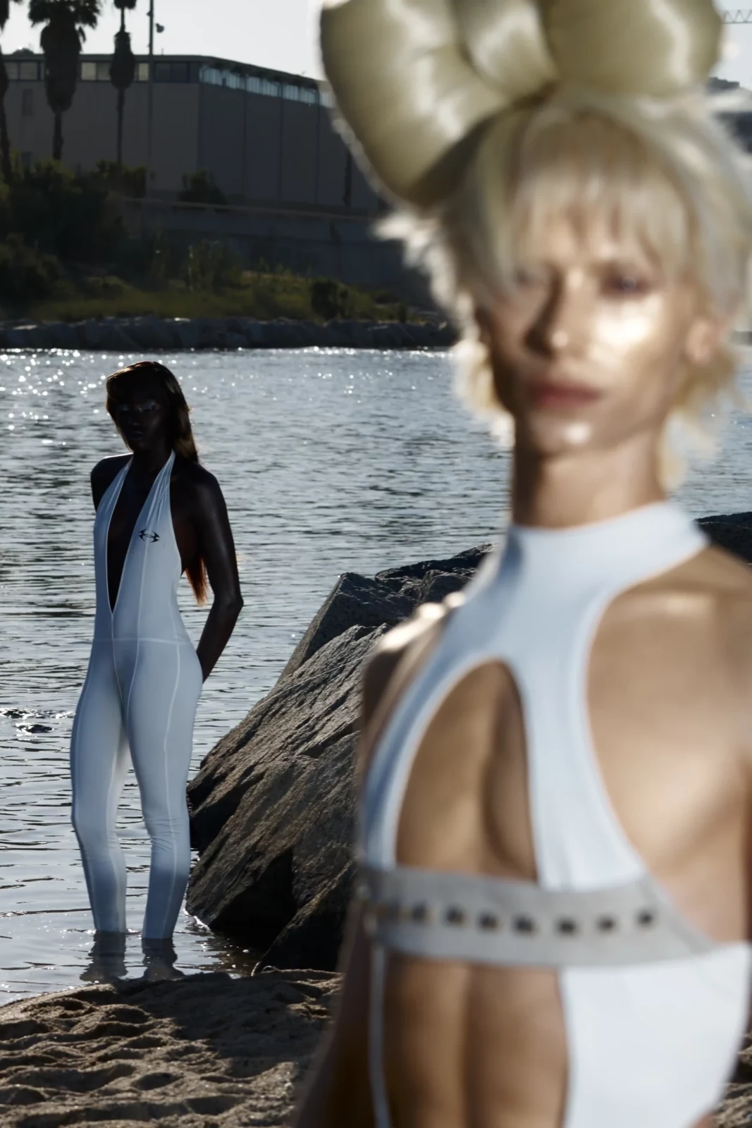 Portrait of a model with sculptural blonde hair wearing a cutout white top by the waterfront.