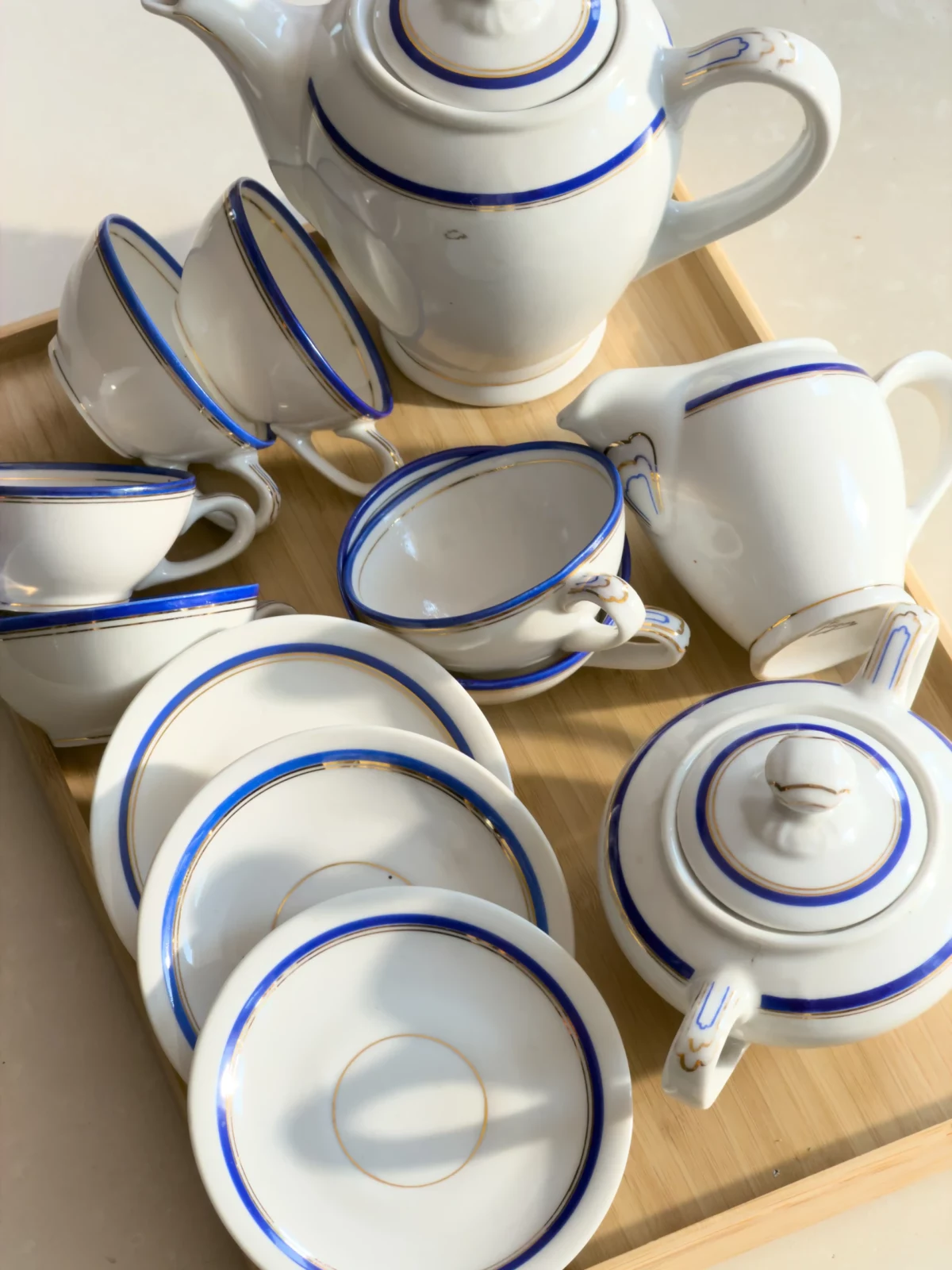 Overhead still life of stacked white cups, bowls and a teapot with blue trim.