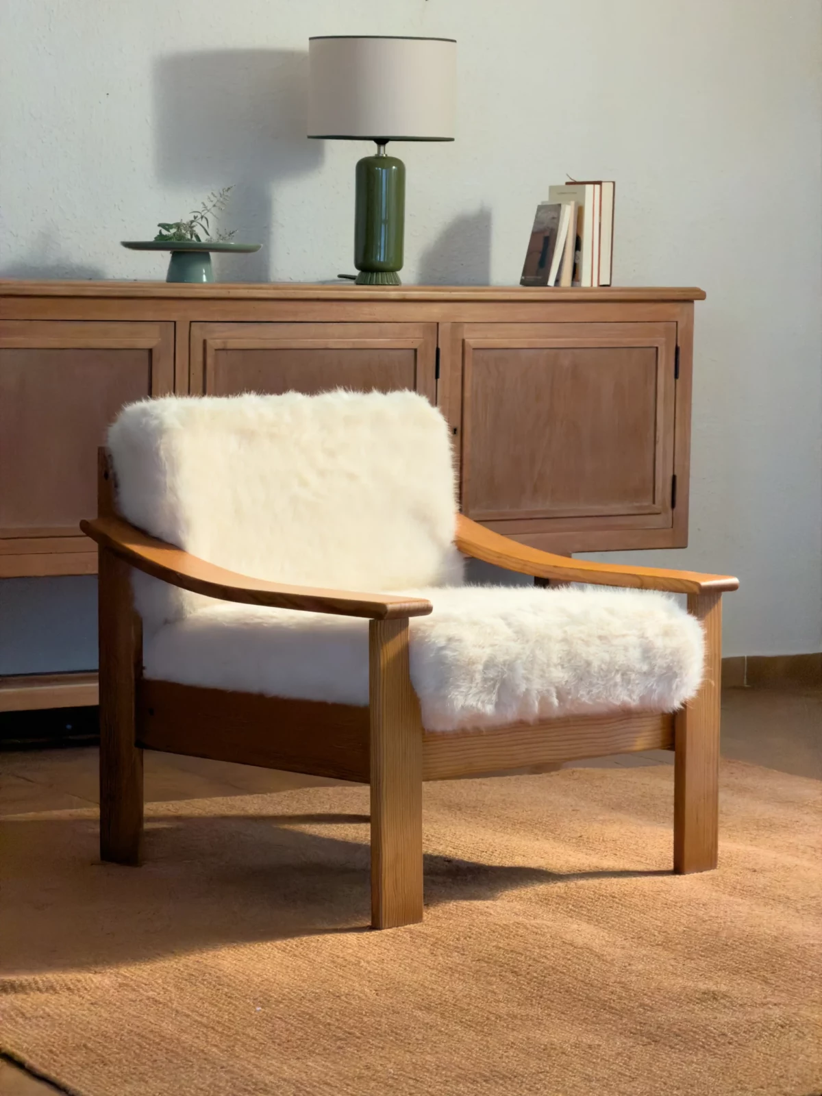 Mid-century wooden lounge chair with white fluffy cushions beside a cabinet and lamps.