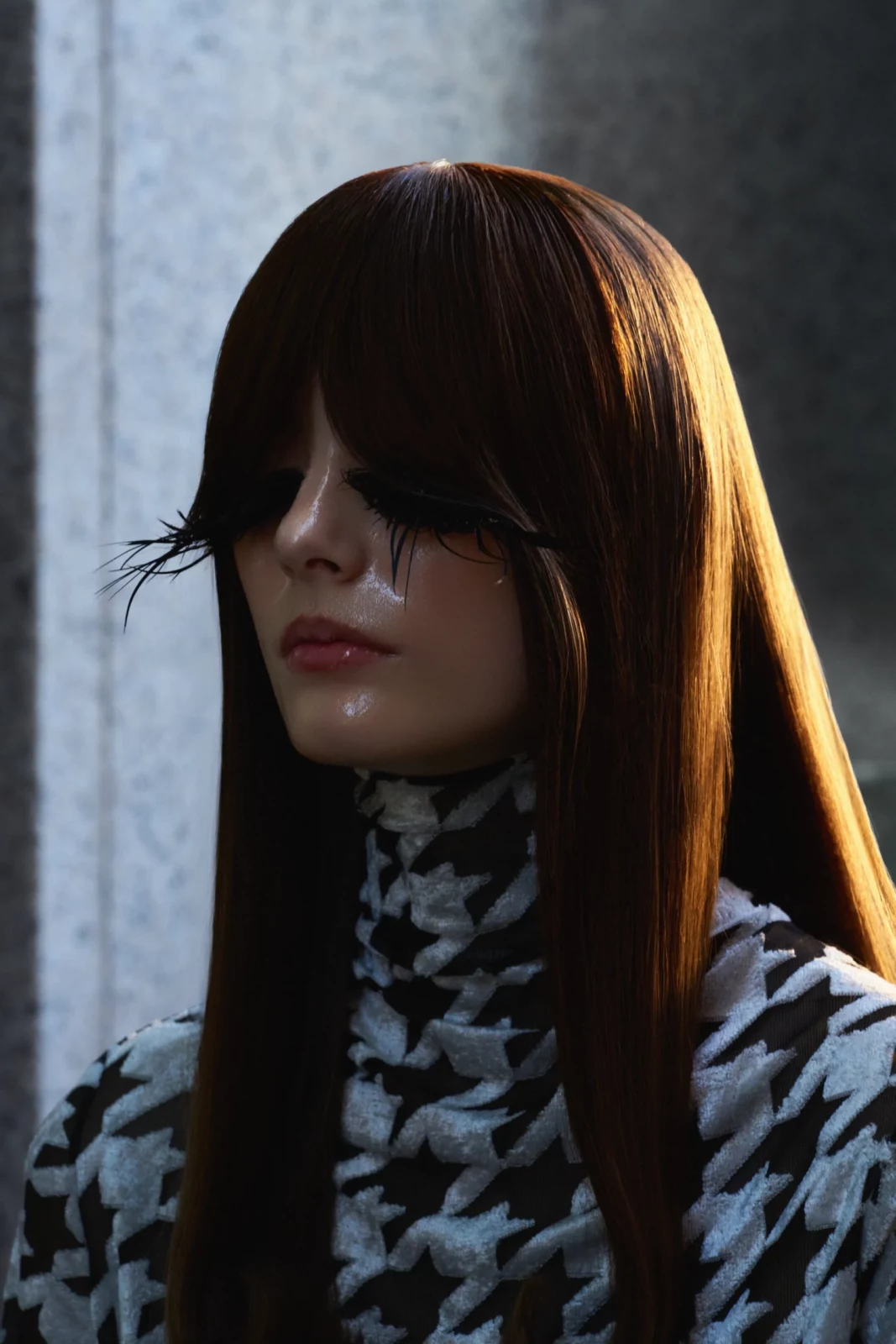 Fashion portrait of a woman with long brown hair and heavy fringe wearing a black-and-white patterned top.