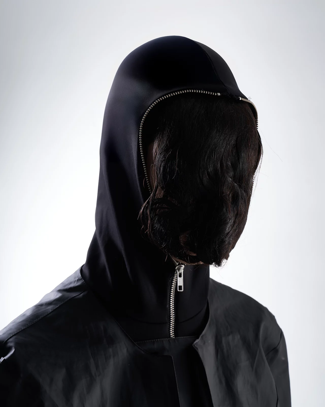Close-up of a hooded model with their face obscured by long dark hair.