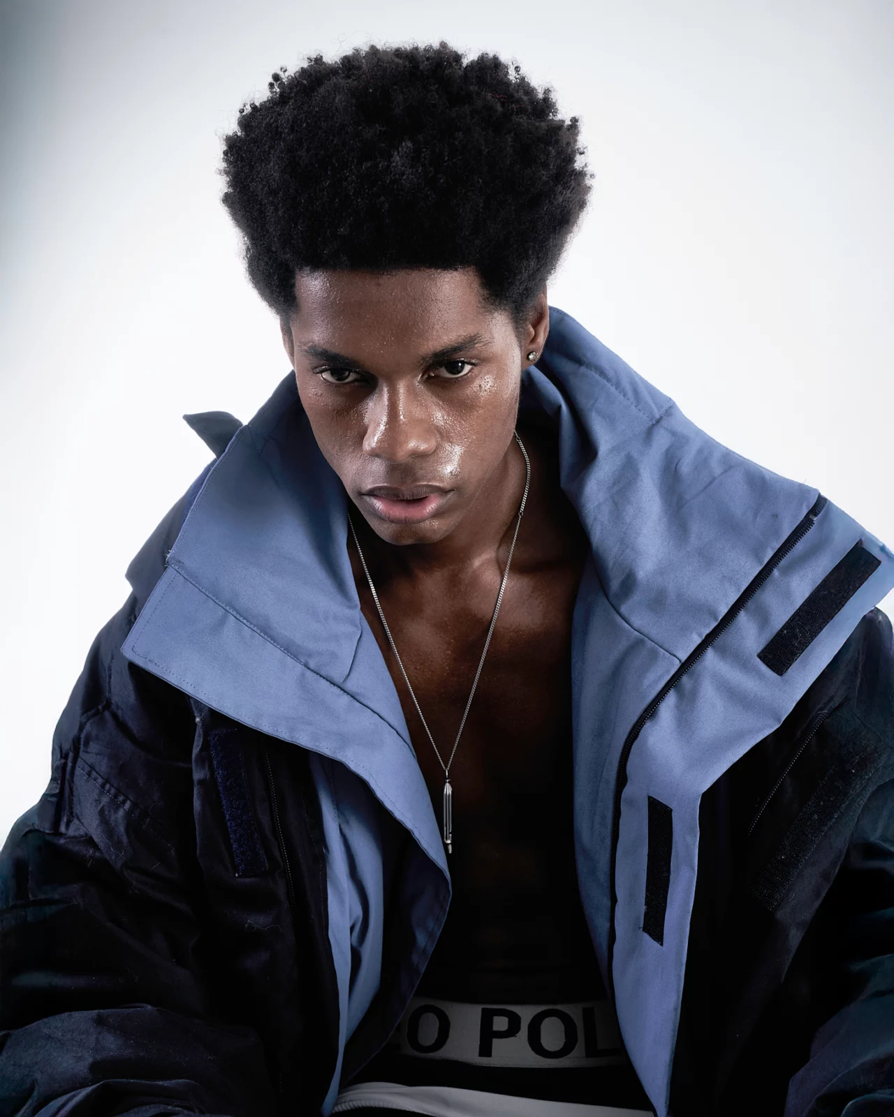 Studio portrait of a model in a layered navy jacket with a dramatic oversized collar.